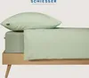 A light green pillow and fitted sheet are neatly arranged on a wooden bed frame. Produktbild-Vorschau