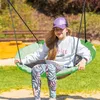 A young girl sits on a green swing in a park setting. Náhľad obrázku produktu