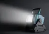 A teal and black Makita LED work light is shown on a dark background, emitting a bright beam of light to the left. Produktbild-Vorschau