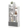 A white, multi-tiered bookshelf with a gray fabric drawer at the bottom, displaying various decorative items and books. Produktbild-Vorschau