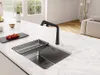 A modern kitchen island with a black faucet and sink, featuring a tray of tomatoes and a bottle of wine in the background. Produktbild-Vorschau