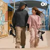 Two children walking with a scooter in an outdoor urban setting. Produktbild-Vorschau