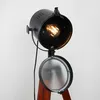 A close-up studio shot of a vintage-style cinema tripod floor lamp with an exposed Edison bulb. Anteprima dell’immagine prodotto