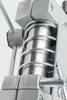 A close-up view of a mechanical device, likely a drill press component, showing a spring mechanism and metal parts. Náhľad obrázku produktu
