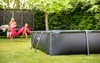 A family is playing in a backyard with a rectangular swimming pool and a trampoline. Produktbild-Vorschau