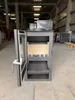 A modern wood-burning stove is displayed in a warehouse setting. Podgląd zdjęcia produktu