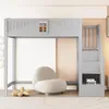 A grey loft bed with stairs and storage, set in a room with a white chair and a rug. Náhled obrázku produktu