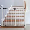 A white metal baby gate is installed at the bottom of a wooden staircase. Náhľad obrázku produktu