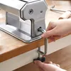 A person is attaching a clamp to secure a pasta maker to a wooden countertop. Produktbild-Vorschau