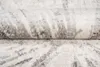 A close-up view of a rolled-up rug with a modern abstract pattern in gray and beige tones. Voir les images du produit
