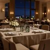 A set table in a restaurant at night, with candles and a bouquet of white roses. Produktbild-Vorschau