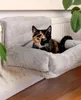 A tortoiseshell cat is resting in a gray, plush cat bed attached to a radiator. Náhľad obrázku produktu