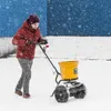 A person is using a spreader in the snow. Produktbild-Vorschau