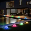A modern house with a swimming pool at night, illuminated by colorful cube-shaped solar lights. Produktbild-Vorschau