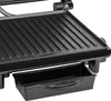 A close-up view of a black electric panini grill, focusing on the ribbed grilling surface and a removable drip tray underneath. Produktbild-Vorschau