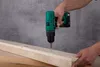 A person is using a cordless drill to screw into a piece of wood. Produktbild-Vorschau