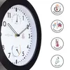 A close-up of a round wall clock with a black frame and white face, displaying time, temperature, and humidity. To the right are circular icons with text describing features like 'Weather proof', 'Outdoor/Indoor', 'Temperature', and 'Humidity'. Náhled obrázku produktu