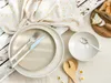 A table setting with plates, cutlery, a bowl, and bread with cheese. Náhľad obrázku produktu