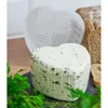 A heart-shaped cheese with herbs and a cheese mold are displayed on a dark surface, with bread in the background. Produktbild-Vorschau