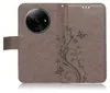 A brown flip case for a smartphone, featuring a floral and butterfly embossed design. Produktbild-Vorschau