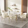 A dining room set with a marble-top table and six beige upholstered chairs with gold legs. Produktbild-Vorschau