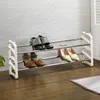 A three-tiered shoe rack holding several pairs of shoes, placed on a wooden floor against a textured wall. Produktbild-Vorschau