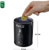 A hand is inserting a coin into a Coca-Cola branded coin bank. Produktbild-Vorschau