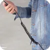 A person in a denim jacket holds a phone connected to a coiled black cable. Anteprima dell’immagine prodotto