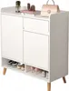 A white cabinet with a drawer and doors, used as a shoe organizer. Decorative items and a handbag are on top. Náhled obrázku produktu