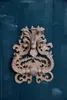 A close-up of an ornate, antique-style bronze door knocker mounted on a dark teal wooden door. Produktbild-Vorschau