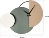 A modern, abstract wall clock with geometric shapes and black hands. Produktbild-Vorschau
