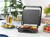 A panini grill with food on it, placed on a kitchen counter with salads and vegetables. Produktbild-Vorschau