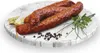 Three sausages are arranged on a marble-patterned platter with bay leaves, peppercorns, and parsley. Náhled obrázku produktu