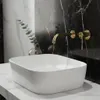 A modern bathroom sink with a gold faucet against a marble-patterned wall. Podgląd zdjęcia produktu