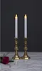Two LED candles in brass candlesticks on a marble surface with a rose and greenery in the foreground. Produktbild-Vorschau