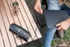 A person is connecting a laptop to a CTEK CS FREE charger on a wooden table outdoors. Anteprima dell’immagine prodotto