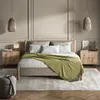 A bedroom scene featuring a bed with green and white bedding, two nightstands, and hanging pendant lights. Náhled obrázku produktu