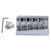 A chrome-finished 5-string bass guitar bridge with a set of screws and an Allen wrench, laid out on a white background. Podgląd zdjęcia produktu