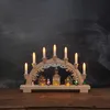 A wooden Christmas arch with illuminated candles and miniature village scene. Podgląd zdjęcia produktu
