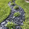 A garden path made of dark stones with grass on the sides. Podgląd zdjęcia produktu