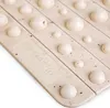 A close-up view of a beige bath mat with raised circular bumps and a textured surface, showing a logo and text. Náhľad obrázku produktu