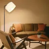 A living room scene with a sofa, armchair, and coffee table, illuminated by a floor lamp. Produktbild-Vorschau