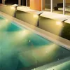 Outdoor solar spotlights illuminating a swimming pool at night. Anteprima dell’immagine prodotto