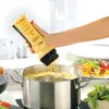 A hand is holding a yellow squeeze bottle over a pot of boiling water, dispensing batter into it. Produktbild-Vorschau