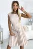 A woman is posing in a room, wearing a dress and holding a clutch. Produktbild-Vorschau