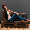 A woman sits on a pallet bench outdoors with fallen leaves around. Podgląd zdjęcia produktu