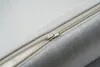 A close-up view of a zipper on a gray fabric surface. Produktbild-Vorschau