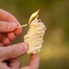 A person is holding a fire starter and lighting it with a match. Podgląd zdjęcia produktu