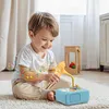 A young boy is playing with a blue toy gramophone on a rug. Náhľad obrázku produktu