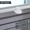 A close-up view of a gray pleated blind mounted on a window frame, with text overlays highlighting product features. Produktbild-Vorschau